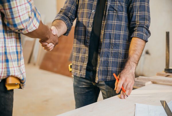 two workers shaking hands as they work on plans for a restaurant chain